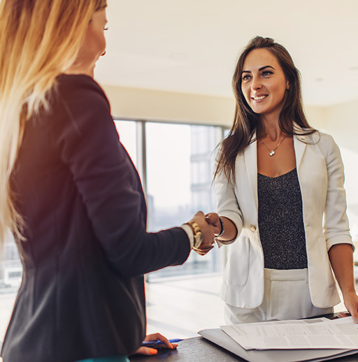 ADMS_Female customer shaking hands with real estate agent agreeing to sign a contract standing in new modern studio apartment