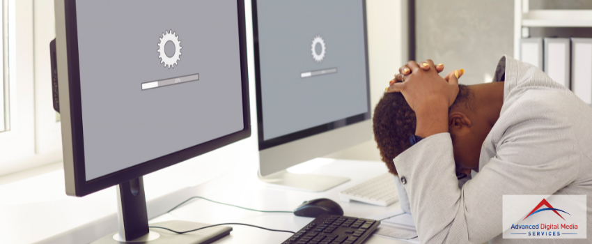 ADMS - A woman frustratedly waiting in front of her two computers