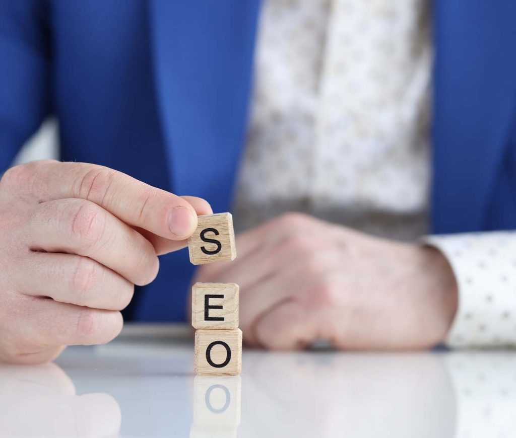 ADMS-Businessman collecting words seo with wooden cubes