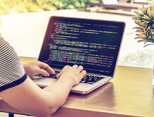 ADMS Close-up of programmer`s hands working on source codes over a laptop on a sunny day