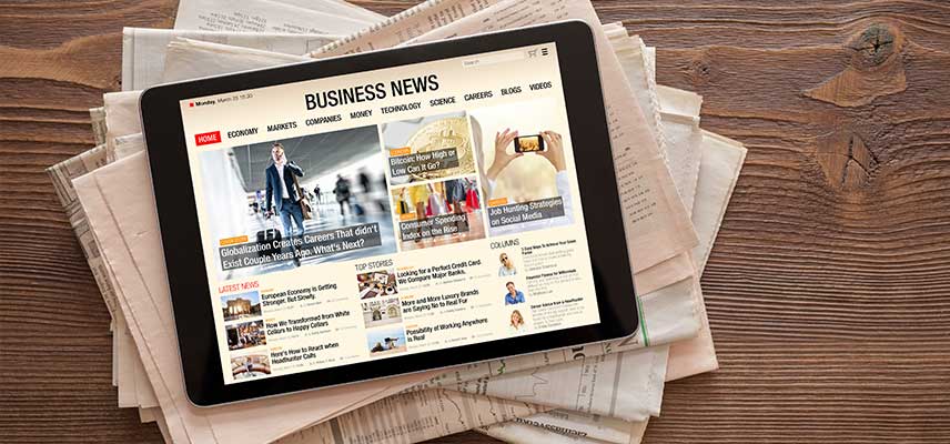 ADMS Tablet with business news website on stack of newspapers
